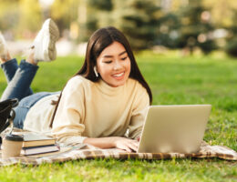 Happy college student girl with laptop preparing for exams outdoors